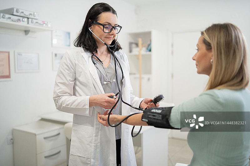 女医生为一名妇女测量血压，作为体检的一部分图片素材