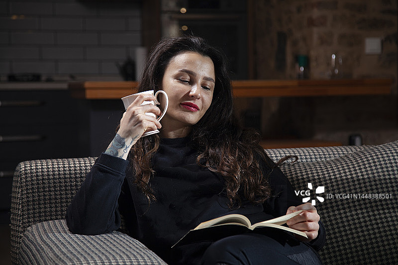 坐在沙发上喝咖啡看书的女人图片素材