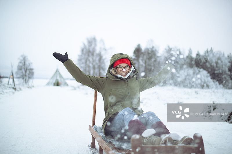 一个快乐的女人在滑雪橇和扔雪，冬日田园牧歌图片素材