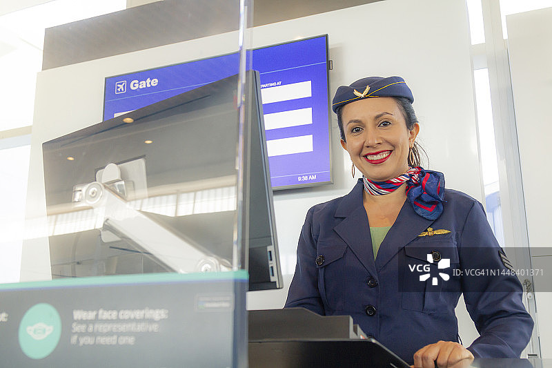 在机场航站楼办理登机手续的美丽拉丁裔空乘人员，欢迎所有顾客或乘客登机。旅行概念。图片素材