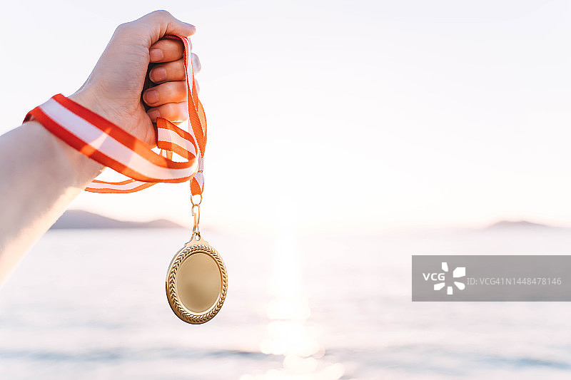 夕阳天空背景下的金牌，胜利的概念图片素材