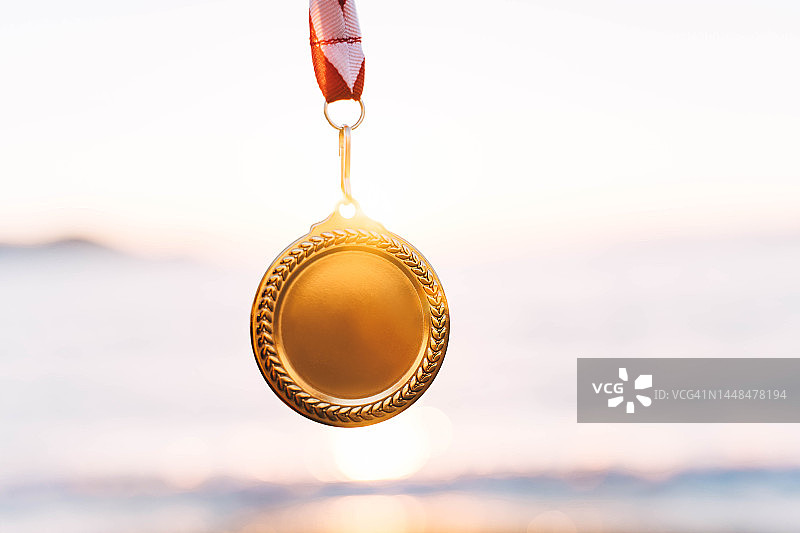 夕阳天空背景下的金牌，胜利的概念图片素材