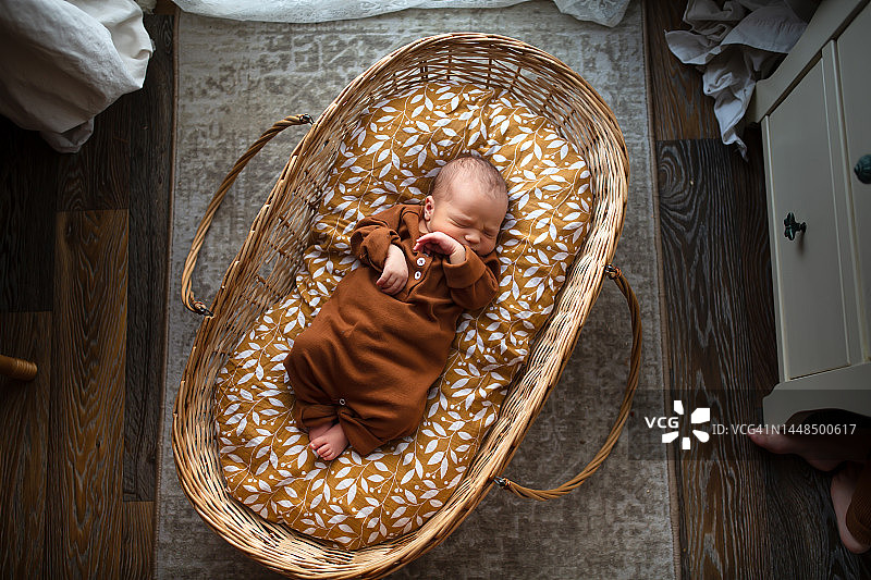 柳条篮子里睡觉的新生儿，穿着有机棉衣服，闭着眼睛躺在棉布尿布上。俯视图图片素材