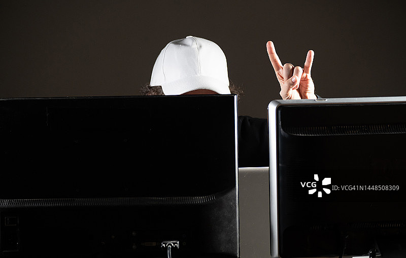 对着三屏笔记本电脑工作，并做出摇滚手势的人图片素材