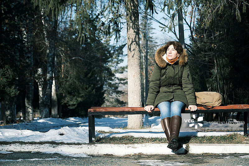 坐在冬季公园长椅上的中年妇女图片素材