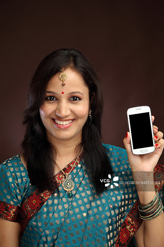 快乐的年轻传统女人拿着手机图片素材