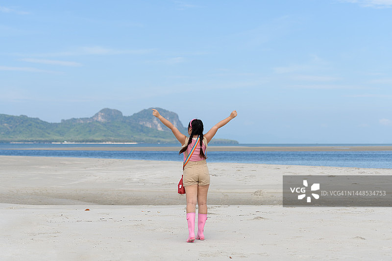 在海滩上伸开双臂的年轻女人图片素材