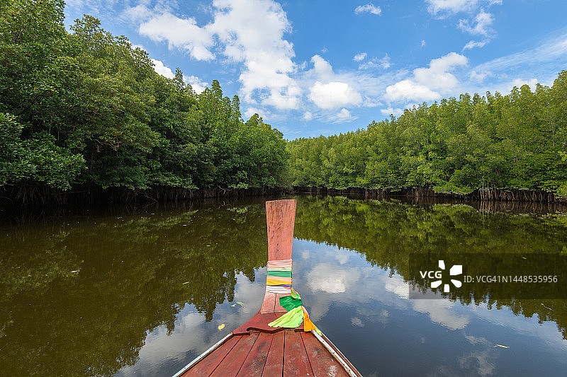 穿梭于红树林中的长尾船，蓝天白云倒映在水面上图片素材