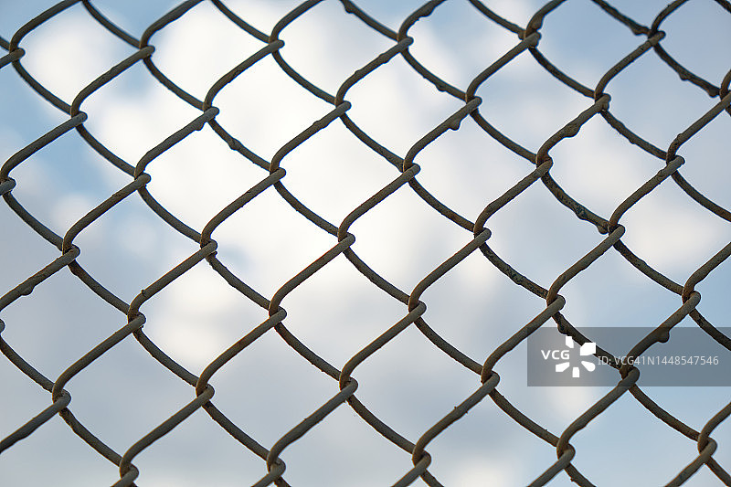 蓝天白云下的金属丝网围栏图片素材