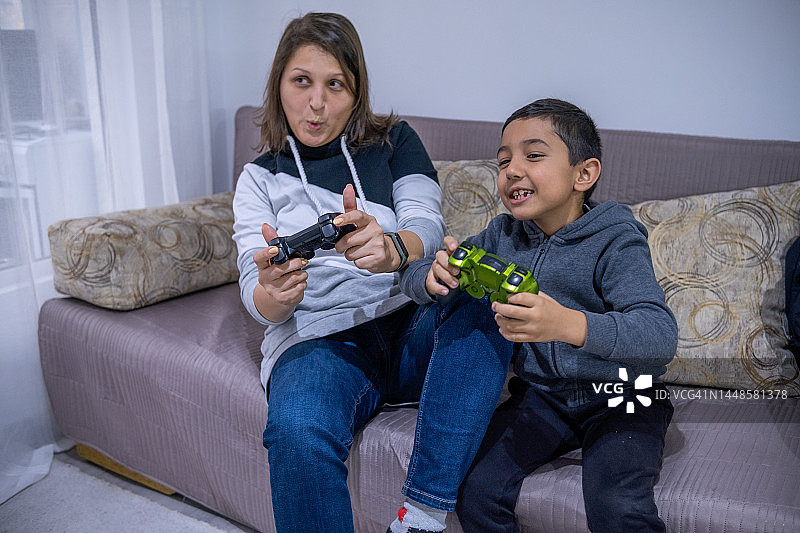 快乐的小男孩和他的母亲一起玩游戏机图片素材