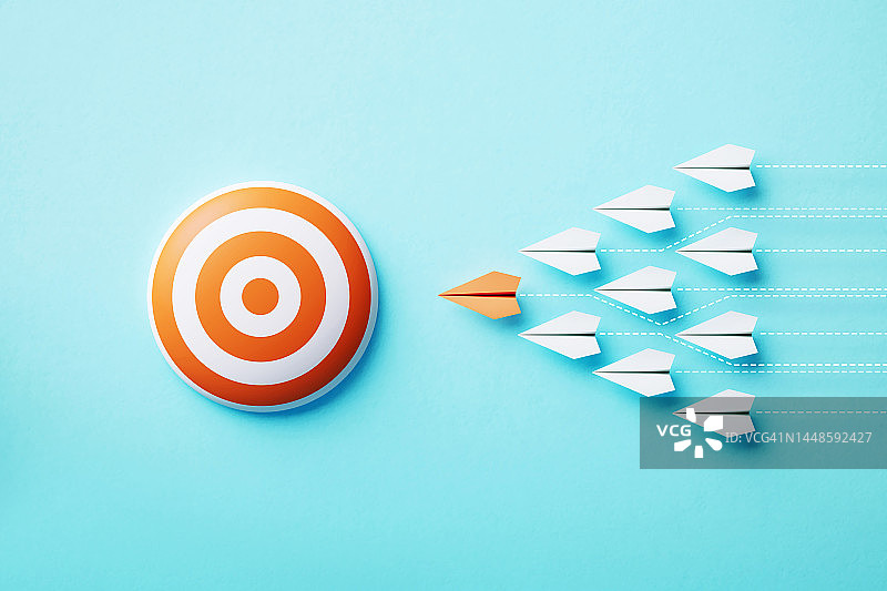 蓝色背景上飞向橙色靶心的纸飞机图片素材