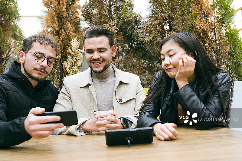 三个年轻的朋友看着智能手机大笑图片素材
