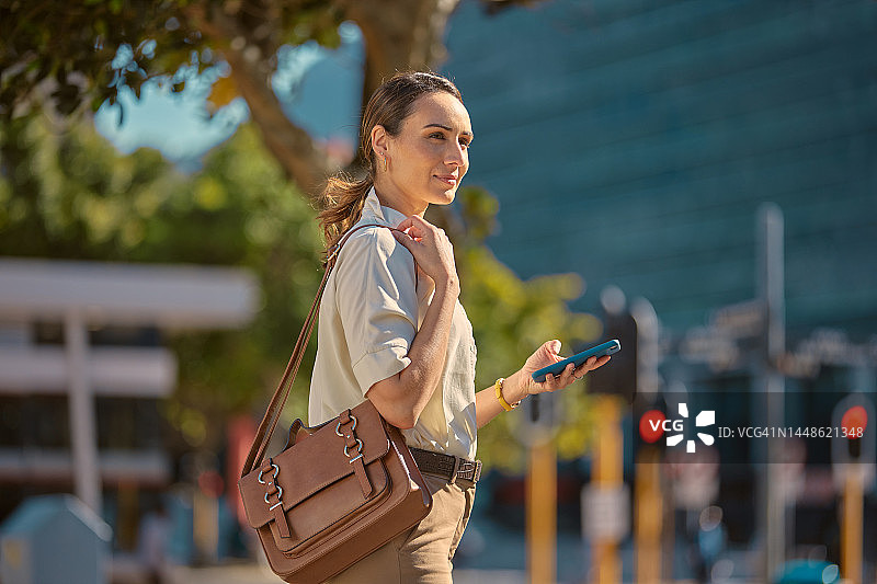 智能手机、行走和城市女商人手机通讯、在线聊天和社交。城市街道，使用手机和企业经理思考户外旅行的职业，带着包图片素材