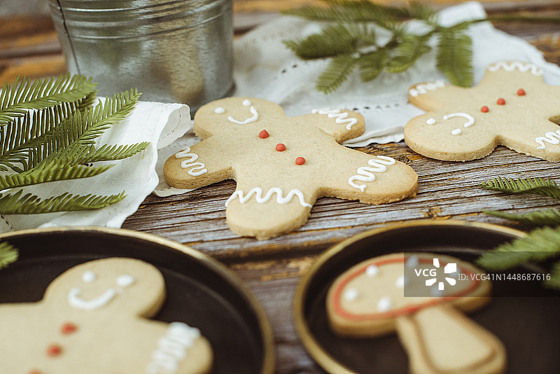 姜饼人和姜饼蘑菇饼干的特写，木桌上有室内植物、冷杉树枝和蕾丝桌布图片素材