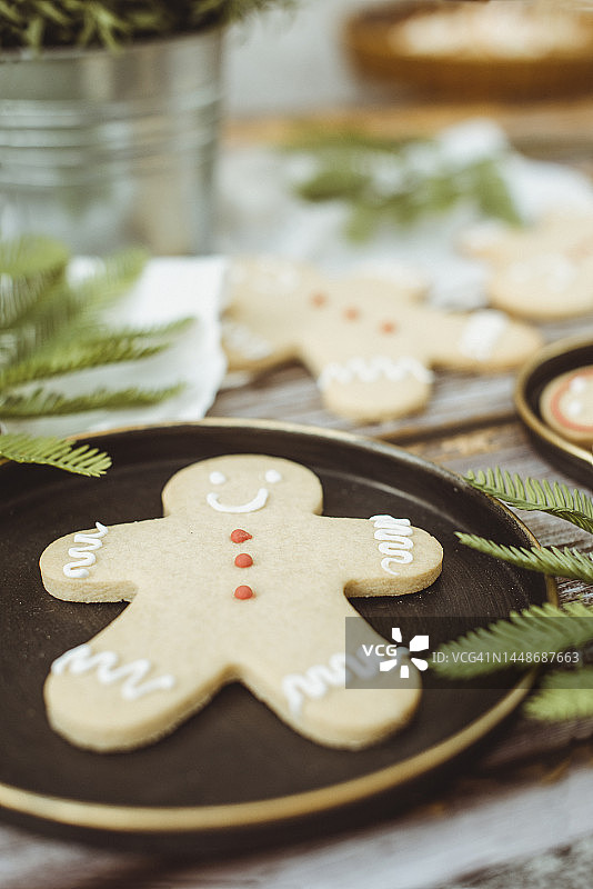 姜饼人在木桌上的特写，有室内植物、冷杉树枝和蕾丝桌布图片素材