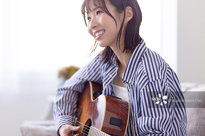 女人坐在沙发上弹吉他图片素材