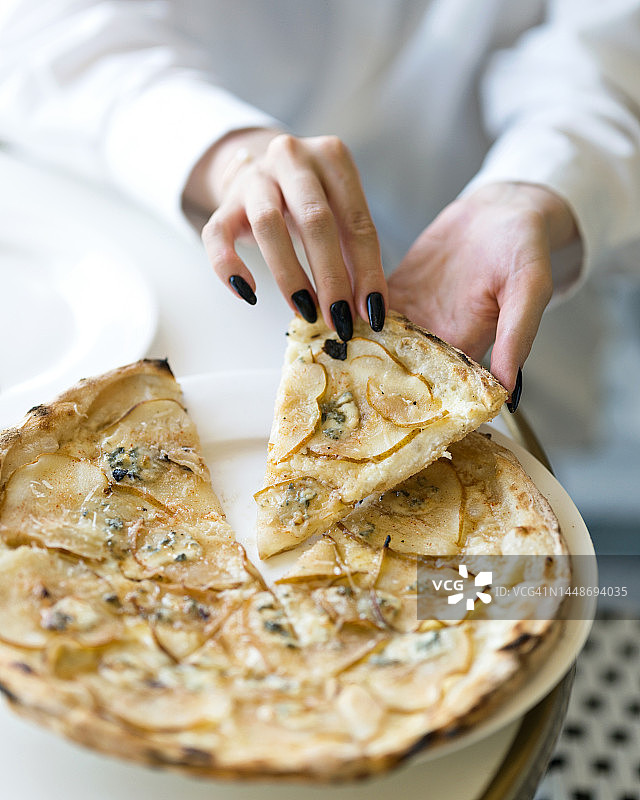 女人在吃披萨，梨披萨切片，意大利美食，素食，柔焦图片素材