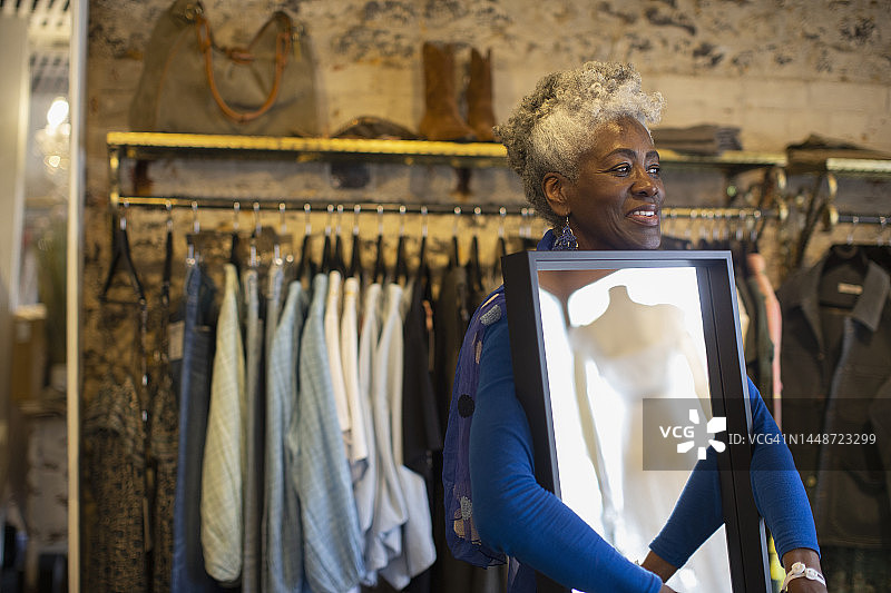 笑容满面的老年女店主在精品店里照镜子图片素材
