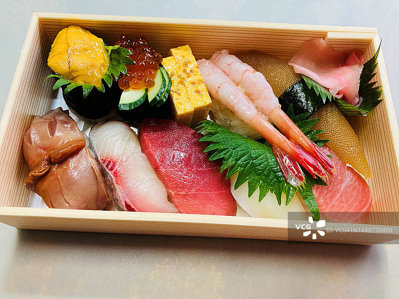 手机拍摄的寿司便当盒:金枪鱼、鲱鱼籽、鱿鱼、甜虾、三文鱼籽、黄尾鱼、海胆、黄瓜煎蛋卷、紫苏叶和腌姜图片素材