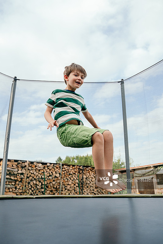 夏天户外蹦床上的白人小男孩图片素材