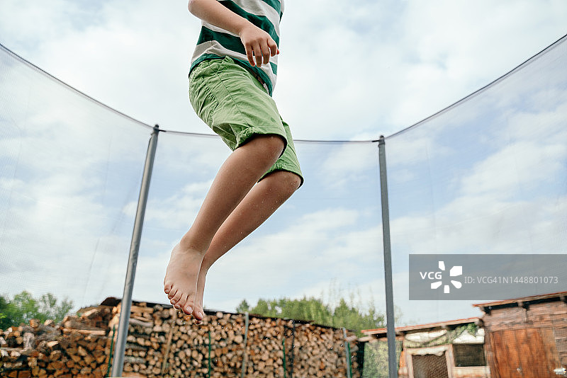 夏季，小男孩在户外蹦床上跳跃（未识别面部）图片素材