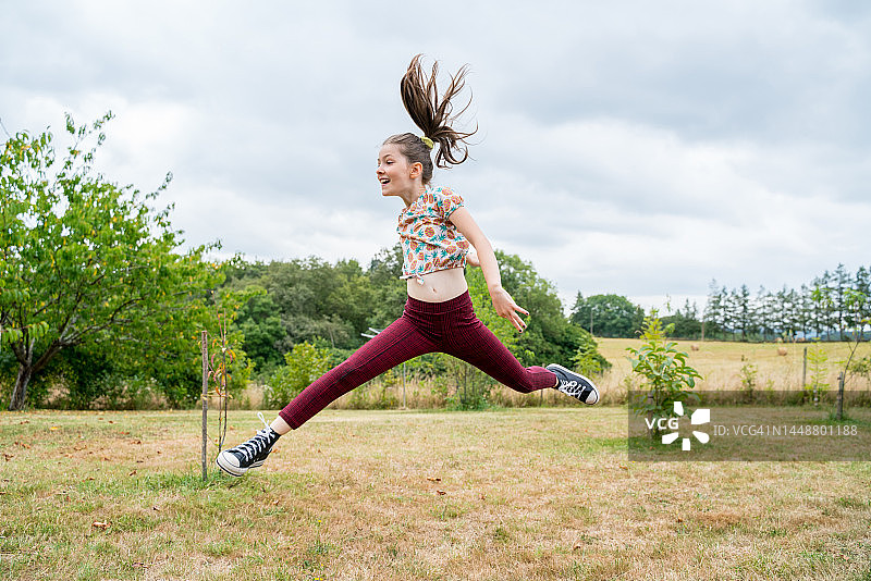 金发小女孩在花园里跳跃图片素材