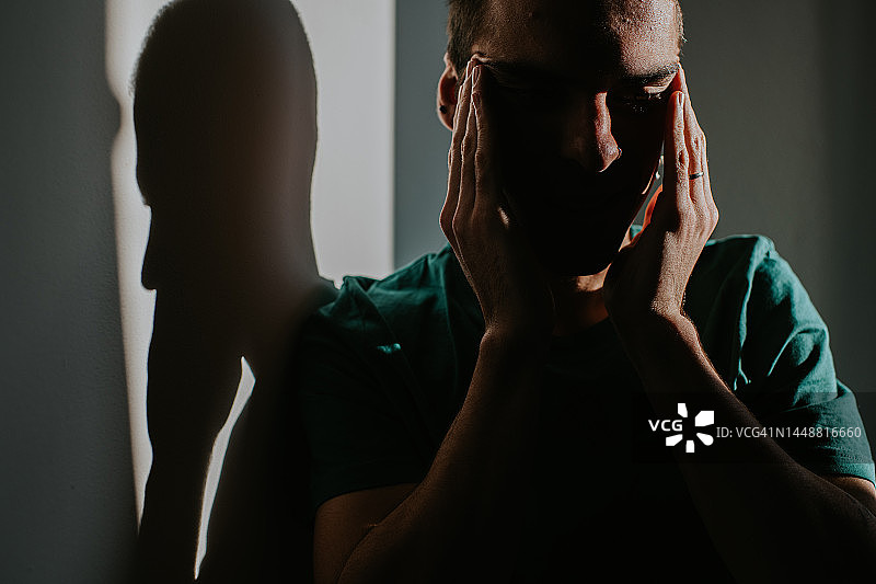 男子揉着太阳穴，似乎感到疼痛或绝望图片素材