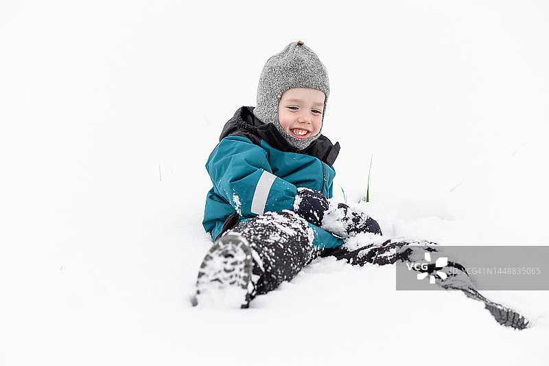 快乐的5岁白人男孩在雪中玩耍图片素材