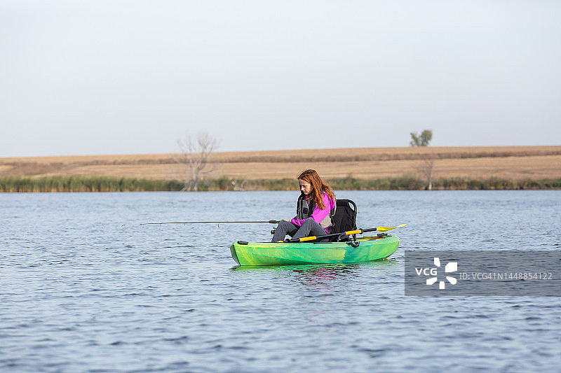 女孩在绿色皮划艇上钓鱼图片素材