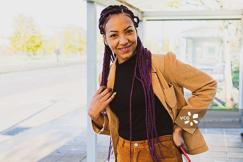 在公共汽车站微笑的拉丁裔商务女人图片素材