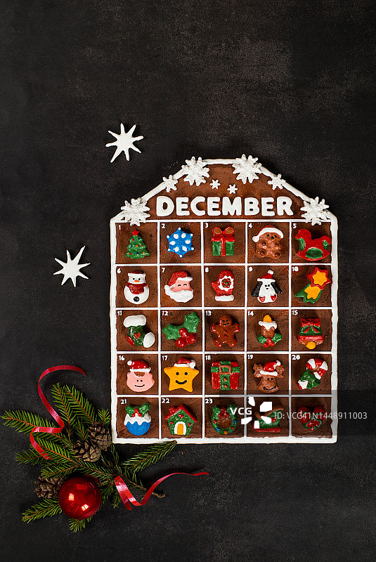 圣诞节降临节日历，由彩色糖霜覆盖的各种圣诞造型糖果制成。深灰色背景，俯视图片素材