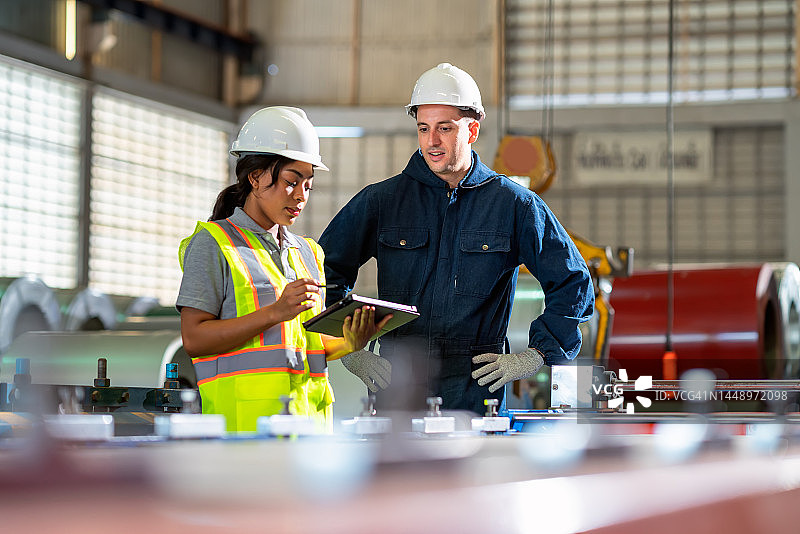 质量控制是产品的主要关口：生产工程师在金属制造厂讨论，男机床操作员向钢厂的女生产工程师讲解钣金冲压工艺图片素材