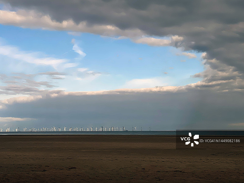 有戏剧性云彩的远处风力发电场图片素材