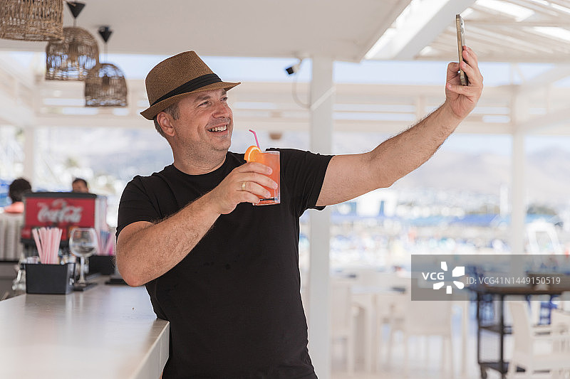 快乐的男人拿着鸡尾酒自拍图片素材
