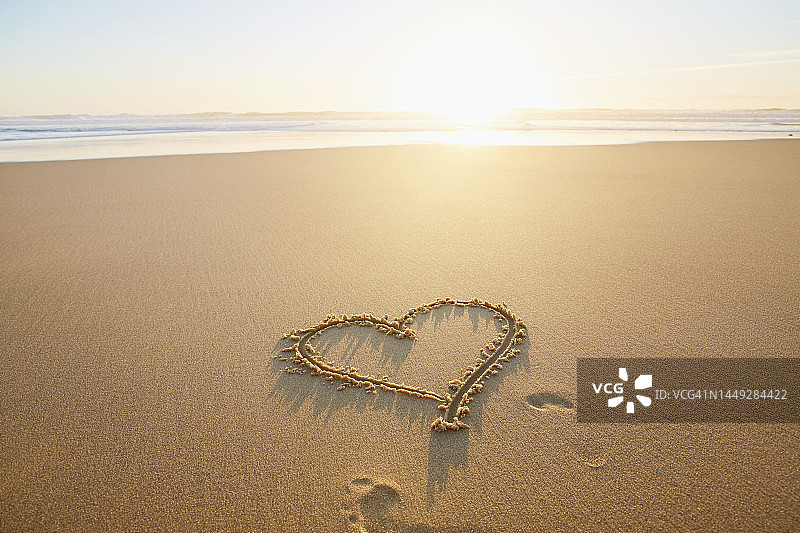 海滩日落时沙滩上画的心形图片素材