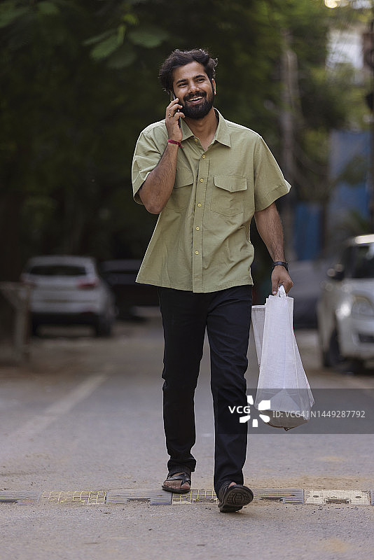 在街上边走边用手机聊天的年轻男人图片素材