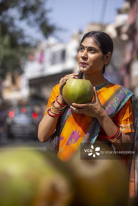 在街上喝绿色椰子水的年轻女人肖像图片素材