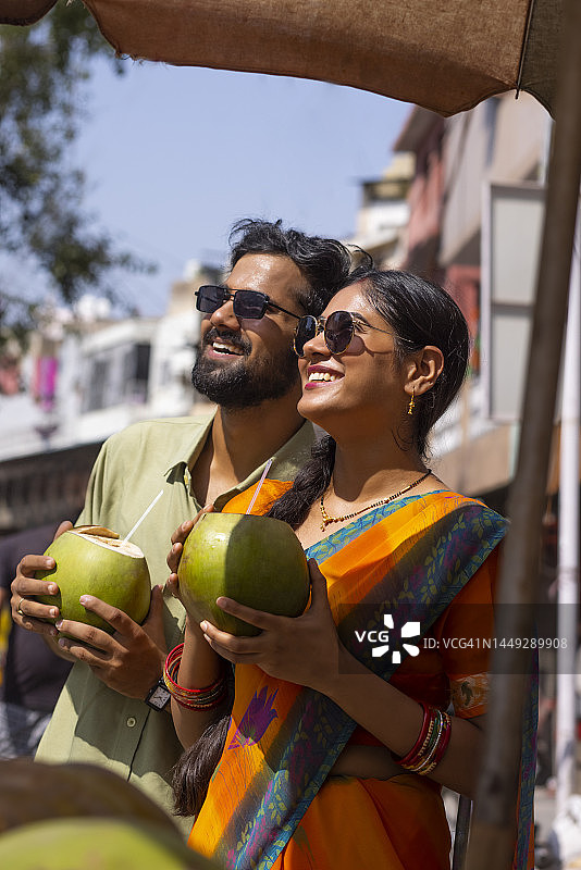 年轻情侣在街头喝绿色椰子汁图片素材