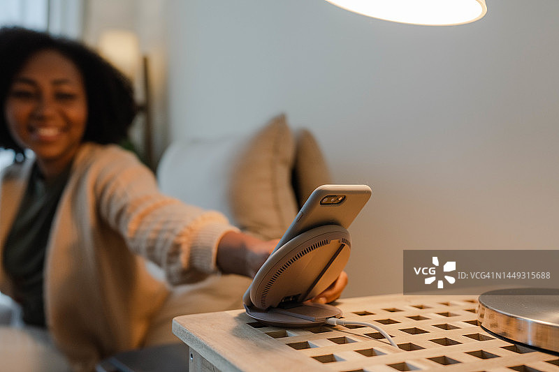 女人将智能手机放在无线充电器上图片素材