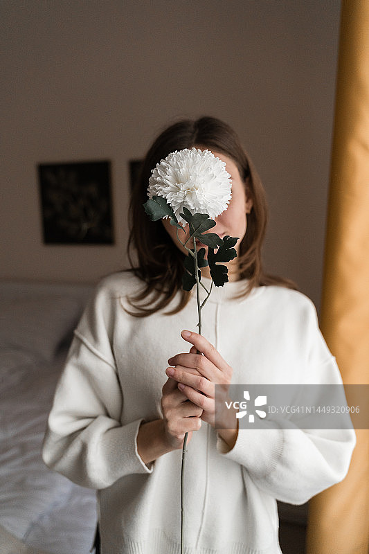 在家中手持白色鲜花的年轻女人。生态可持续生活图片素材