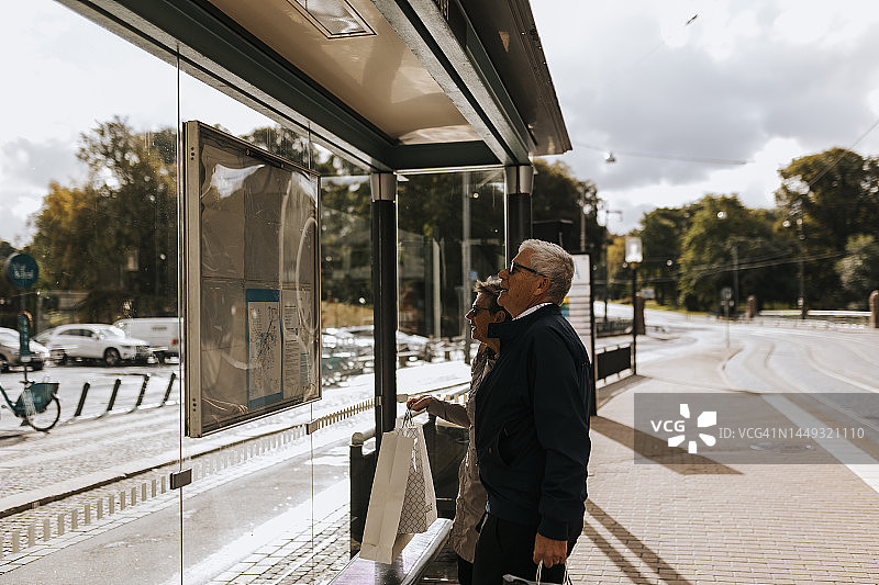 年长夫妇在巴士站看时间表图片素材