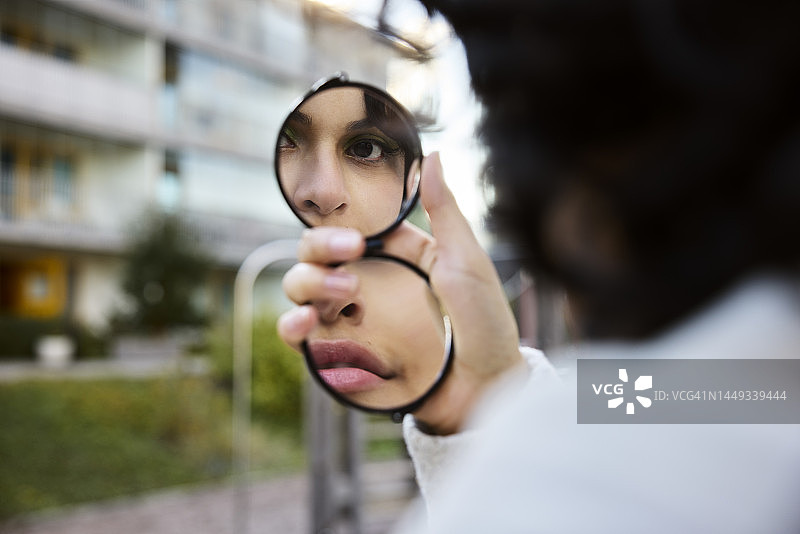 年轻女子在手镜中映出倒影图片素材