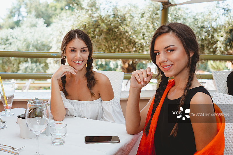 在餐馆餐桌旁喝着餐前饮品的快乐年轻女人们图片素材