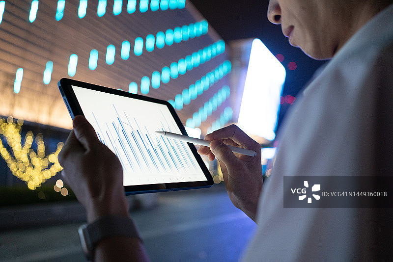 在户外夜晚使用平板电脑的亚洲男人图片素材