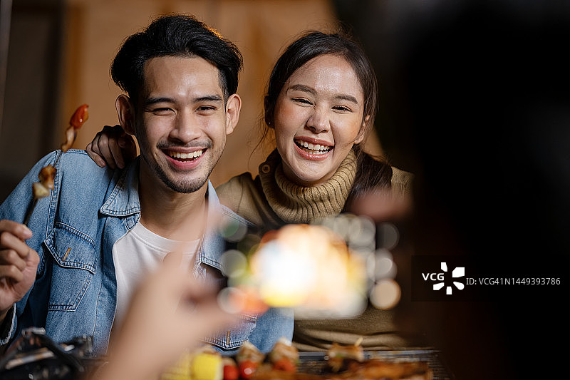 科技与快乐：亚洲朋友在户外露营，有人用智能手机拍照图片素材