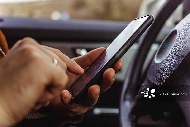 在车里用智能手机发信息、进行在线支付和购物的络腮胡男人图片素材