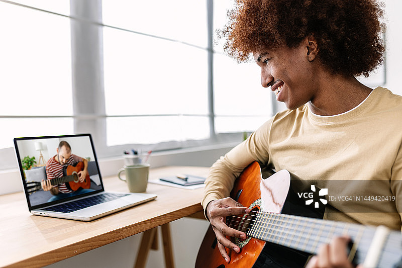 年轻非裔美国男学生通过视频会议，在家用笔记本电脑向中年教师学习弹吉他。教育和在线学习概念。图片素材