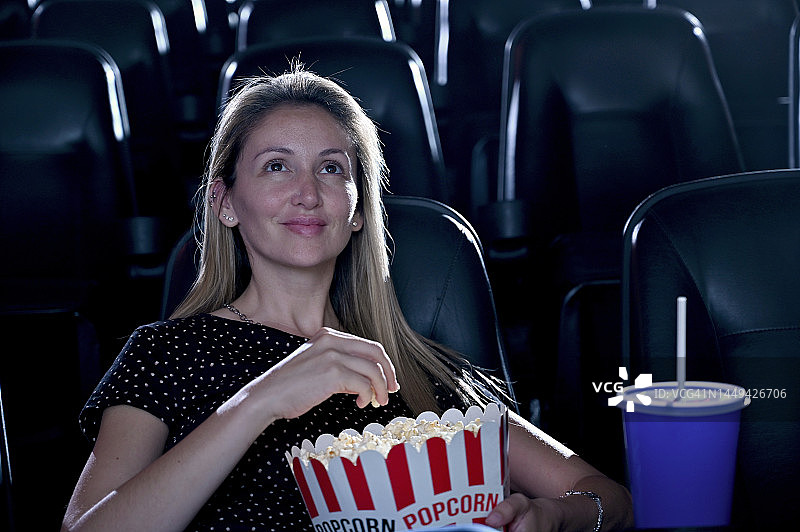 独自在电影院吃爆米花的女人图片素材