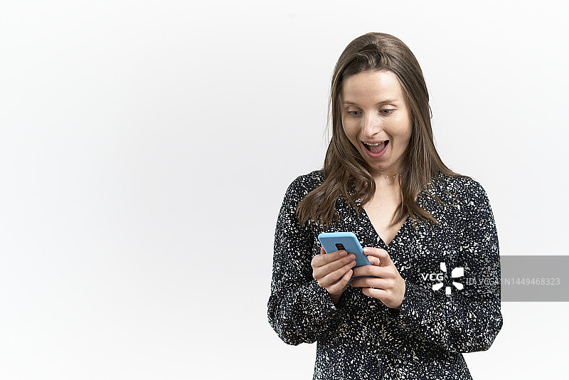 穿连衣裙的女子惊讶地看着手机，白色背景图片素材