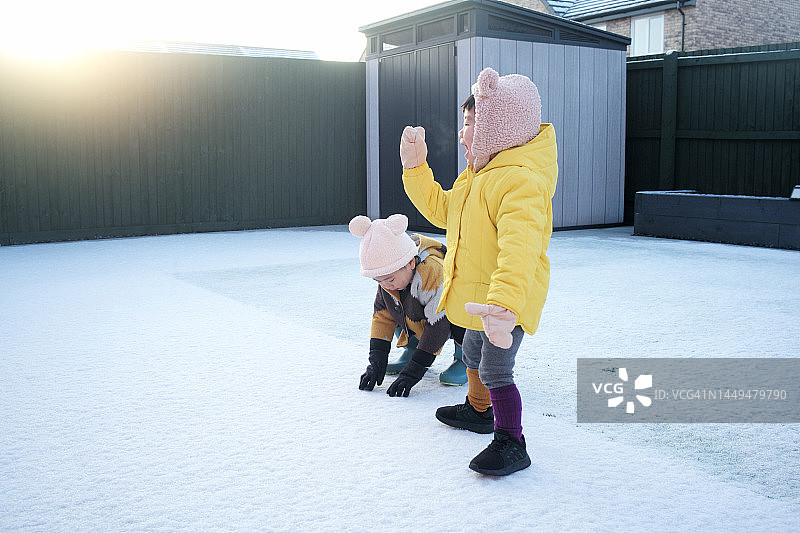 在冬季假期玩耍的亚洲男孩和女孩，在雪地上奔跑图片素材